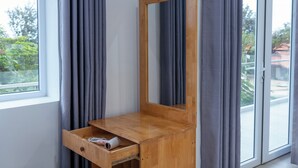 A room with a wooden desk, a mirror, a small wooden stool, and a window with curtains. - The Thousand Village (Mui Ne)