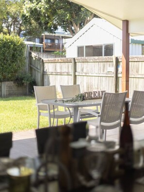 Eine Terrasse im Freien mit Tisch und Stühlen, ein Holzzaun und ein Haus im Hintergrund.