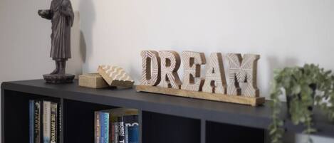 A bookshelf with books, a statue, and wooden letters spelling 'DREAM' on a wall.