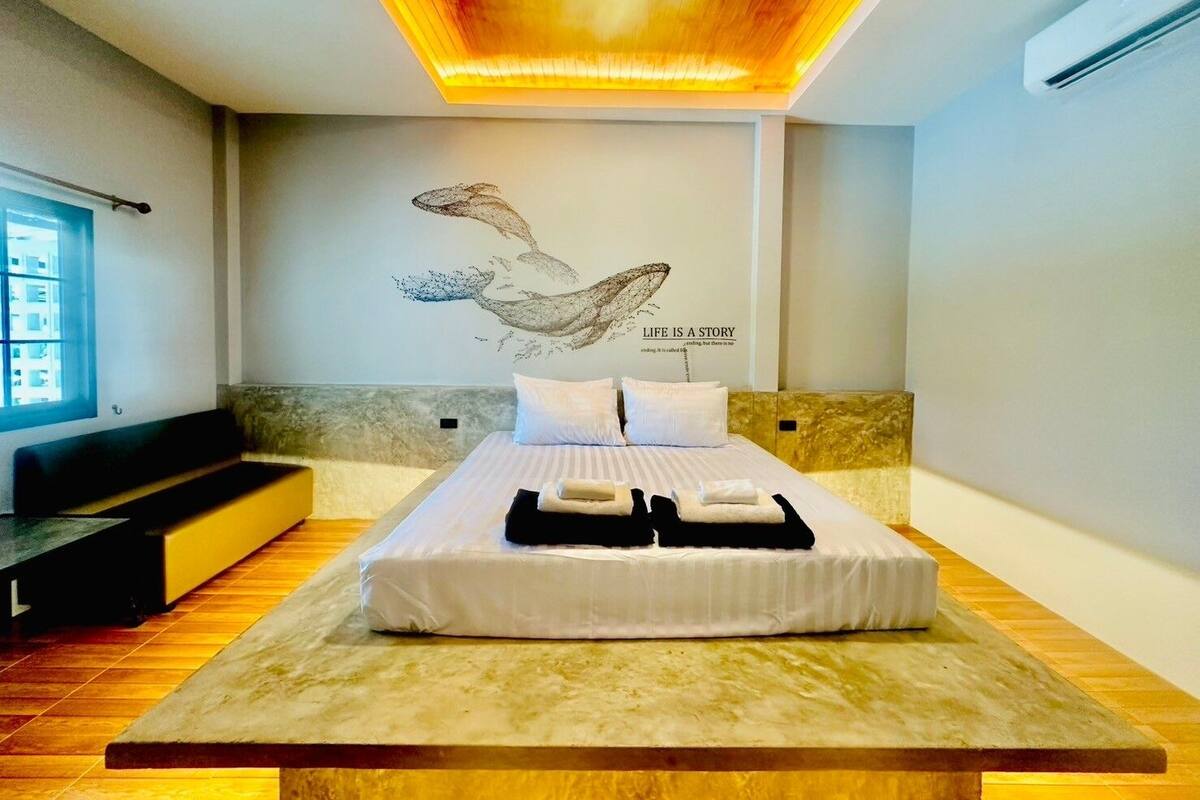 A modern bedroom with a large bed, a mural on the wall, and a ceiling light fixture.