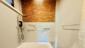 Une petite salle de bain avec une baignoire blanche, une douche et un mur en briques.