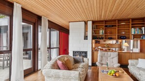 Ein modernes Wohnzimmer mit Kamin, Holzregalen und einem großen Fenster.
