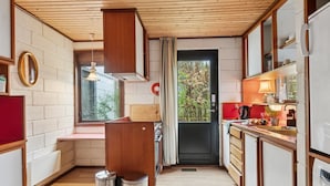 Eine kompakte Küche mit Holzausstattung, einem Einbauofen und einem Fenster mit Blick auf Bäume.