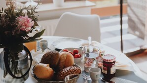 Una mesa de desayuno con diversas opciones de comida, un jarrón de flores y vistas al exterior.