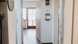 Un pasillo con una puerta que da a una habitación, un cuadro en la pared y una decoración con un flotador de salvamento.