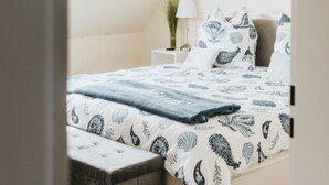 Un dormitorio con cama, mesita de noche, lámpara y ventana.