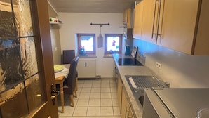 A compact kitchen with a stove, sink, and cabinets. There is a window with a view of the outside. - Vacation apartment for 2 persons, 50 m², 1 separate bedroom, balcony (Inzell)