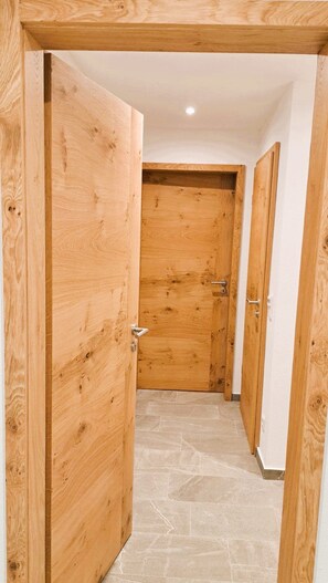 A wooden door with a metal handle, leading to a hallway with stone flooring.