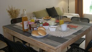 A breakfast table with various food items, a bottle, and a glass of orange juice. - Air-conditioned house Gorges de l'Ardèche, pets welcome (Chauzon)