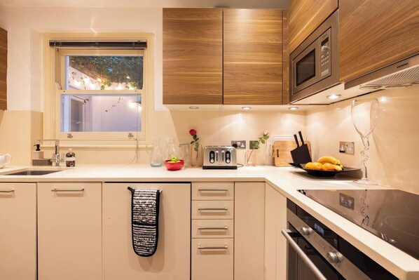 A modern kitchen with wooden cabinets, a built-in microwave, a toaster, and a sink.