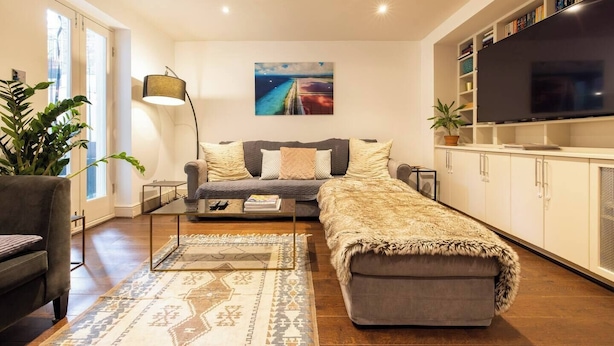 A modern living room with a sofa, a coffee table, a TV, and a bookshelf.