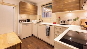 A modern kitchen with wooden cabinets, a built-in oven, a sink, and a window providing natural light.