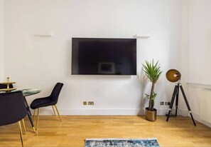 Relax in this stylish living room with a large flat-screen TV, comfortable chair, and a potted plant.