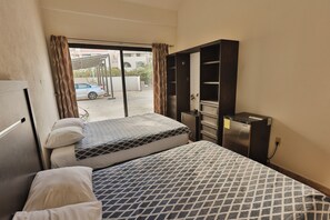 Une chambre d’hôtel avec deux lits, une armoire, un réfrigérateur et une vue sur la rue.