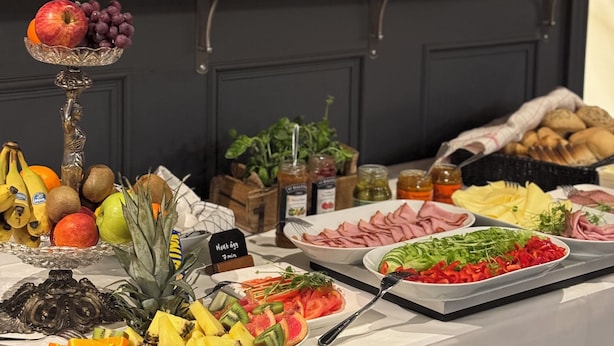 Una mesa de buffet con diversos alimentos, entre ellos frutas, verduras y carnes.