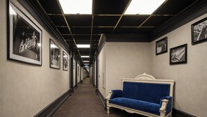 Un pasillo con cuadros enmarcados en las paredes, un sofá azul y una alfombra estampada.