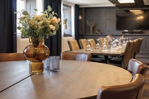 Comedor con una mesa redonda, sillas, un florero con flores y una copa.