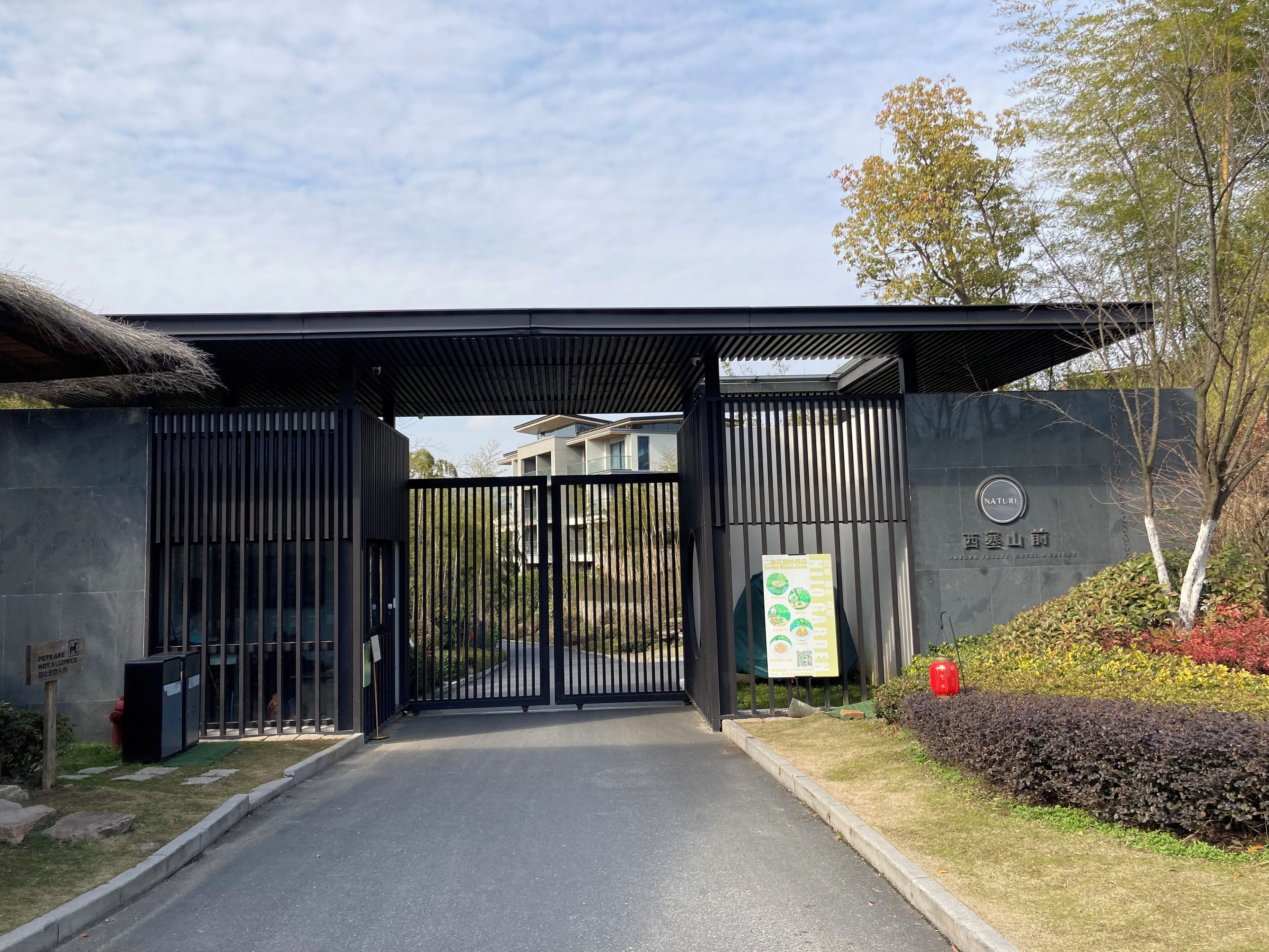 Uma entrada protegida por portão para um edifício com design moderno, com portão de metal e galeria coberta.