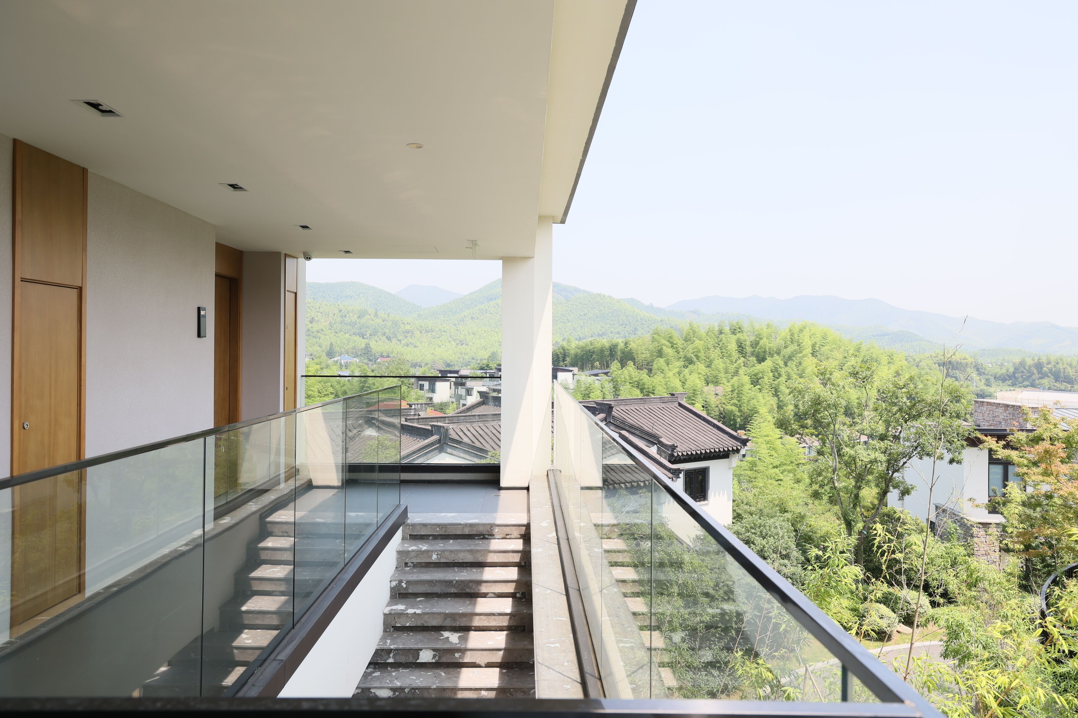 Een modern gebouw met een glazen balkon met uitzicht op een bergachtig landschap.