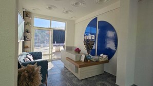 A reception area with a modern design, a reception desk, a seating area with a sofa, and a large window providing a view outside.