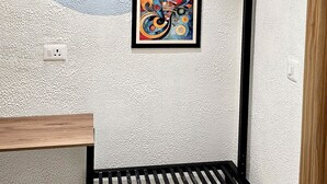 A bunk bed with a metal frame and a wooden bench below. There is a framed abstract painting on the wall above the bed.