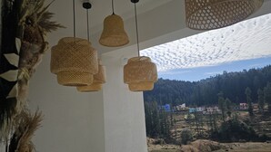 A room with woven pendant lights and a view of a mountainous landscape.