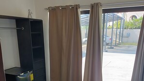 A bedroom with a bed, a wardrobe, and a window with curtains.