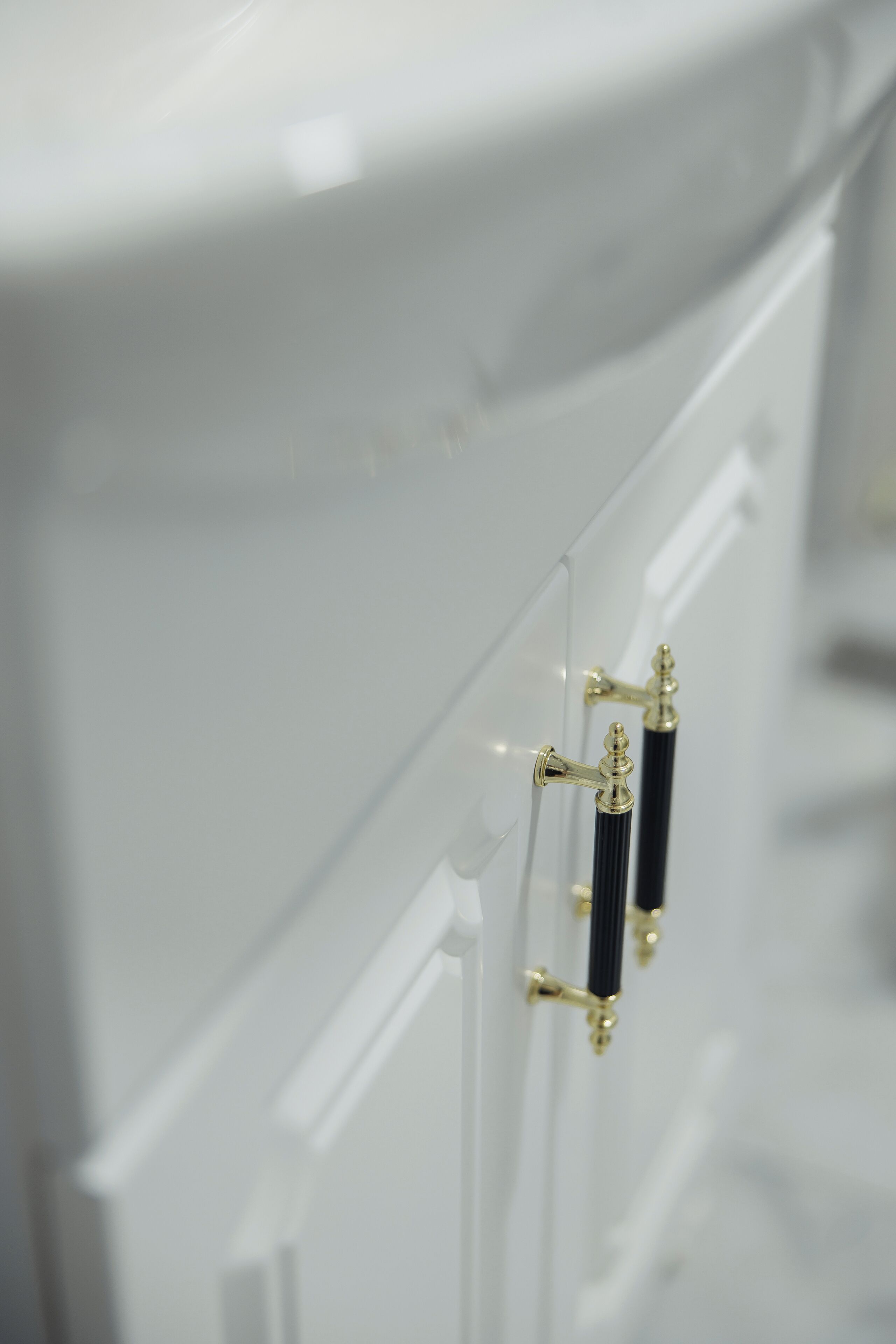A white bathroom with a modern design, featuring a toilet with a gold handle and a black pipe.