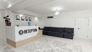 A reception area with a reception desk, a black sofa, a chandelier, and clocks displaying different cities. - Polar Bear (Samarkand)