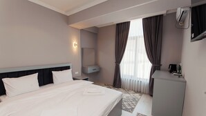 A hotel room with a large bed, a bedside table, a desk, a chair, a mirror, and a window with curtains. - Polar Bear (Samarkand)