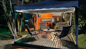 An outdoor patio with a covered seating area, a table, and chairs. - Alemão Cabanas (São Sebastião)