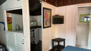 A compact room with a kitchenette, a small table, and a bed. - Alemão Cabanas (São Sebastião)