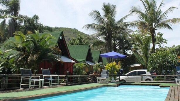 A pool area with lounge chairs, umbrellas, and palm trees. - Alemão Cabanas (São Sebastião)