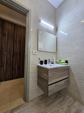 A modern bathroom with a wooden vanity, a large mirror, and a ceiling light. - Charming villa on the dream island of Djerba (Tunis)