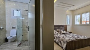 A modern bathroom with a glass shower enclosure, a toilet, and a sink. - Charming villa on the dream island of Djerba (Tunis)