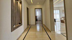Un couloir moderne avec un plancher poli, un éclairage encastré et un mur d’accent en bois.