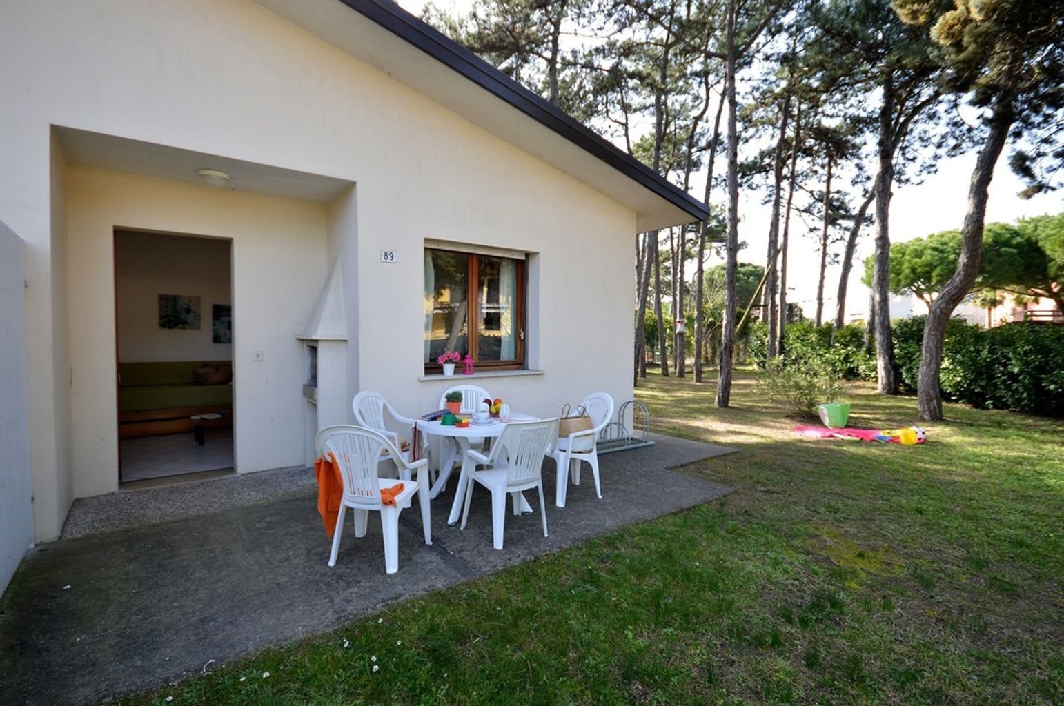 Ein modernes Haus mit Terrasse, weißen Stühlen und einem kleinen Tisch.