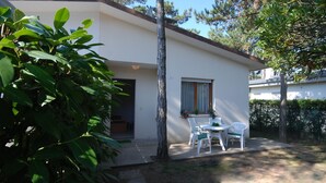 A white building with a small patio area, a window with curtains, and a door.