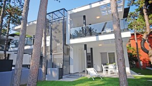 Una casa moderna de dos pisos con un balcón, una zona de estar cubierta al aire libre y un césped cuidado.