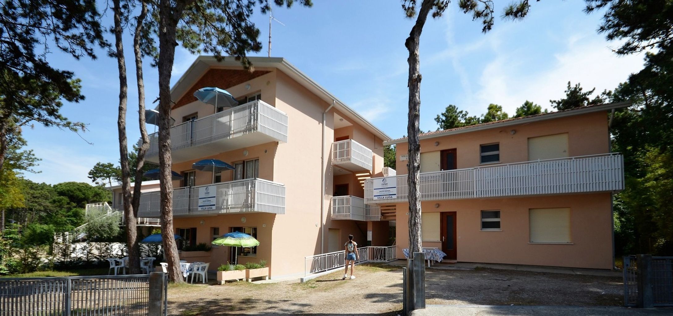 Un edificio de varios pisos con balcones, mobiliario exterior y cielo despejado.