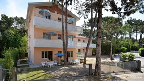 A multi-story building with balconies, outdoor seating, and a sign indicating a restaurant. - Lovely apartment near the sea in Lignano (Lignano Sabbiadoro)