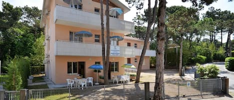 A multi-story building with balconies, outdoor seating, and a sign indicating a restaurant.