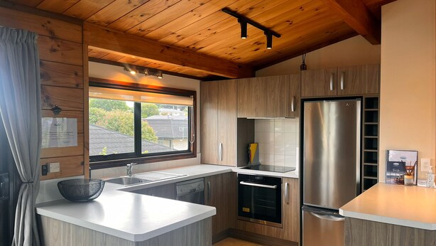 Une cuisine moderne avec des meubles en bois, un réfrigérateur en acier inoxydable et un four encastré.