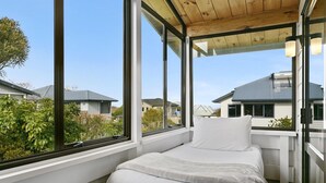Une chambre avec une grande fenêtre, un lit et un plafond en bois.