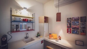 A compact kitchen with a sink, a coffee machine, and a shelf with glassware and mugs. - Antwerp For Two B&B for value seekers (Antwerpen)