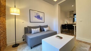 A modern living room with a grey sofa, a white coffee table, and a floor lamp. - w* | Majestic 2BR at Palacio Real (Madrid)