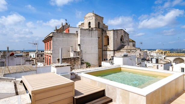 A rooftop terrace with a swimming pool, a wooden deck, and a view of historic buildings. - buone maniere exclusive room (Martina Franca)