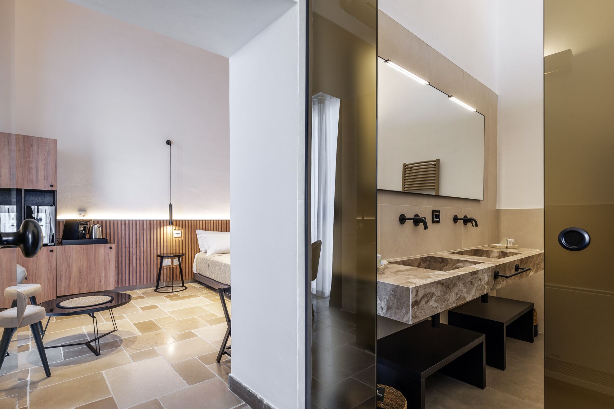 Un baño moderno con un espejo grande, dos lavamanos y un perchero para toallas.