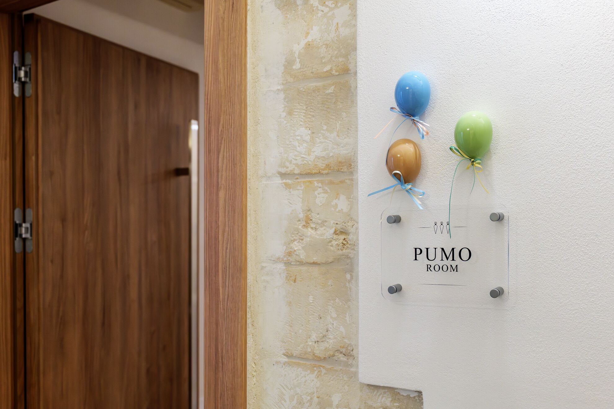 Un letrero en la pared con globos y el texto 'PUMO ROOM'.