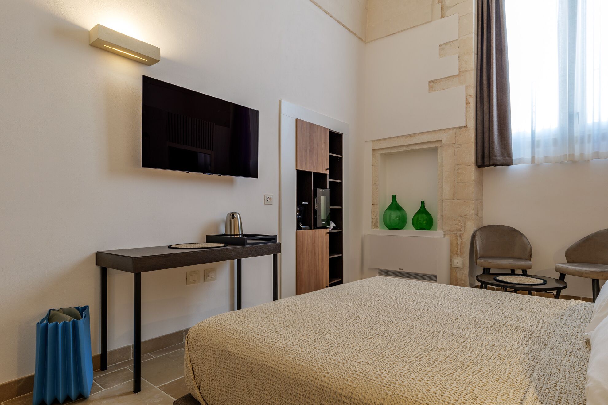 Una habitación de hotel con cama, escritorio, televisor, chimenea y dos sillones.